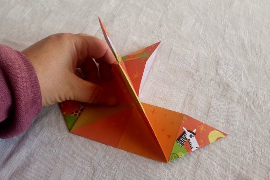 Prendre la pointe en haut à droite pour la rabattre vers le bas à gauche