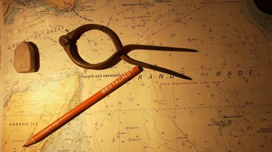 Le compas à pointes sèches et ses accessoires à la lumière de la table à carte