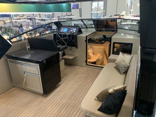 Un flybridge spacieux avec bar, poste de pilotage et banquette latérale et un accès dans la timonerie